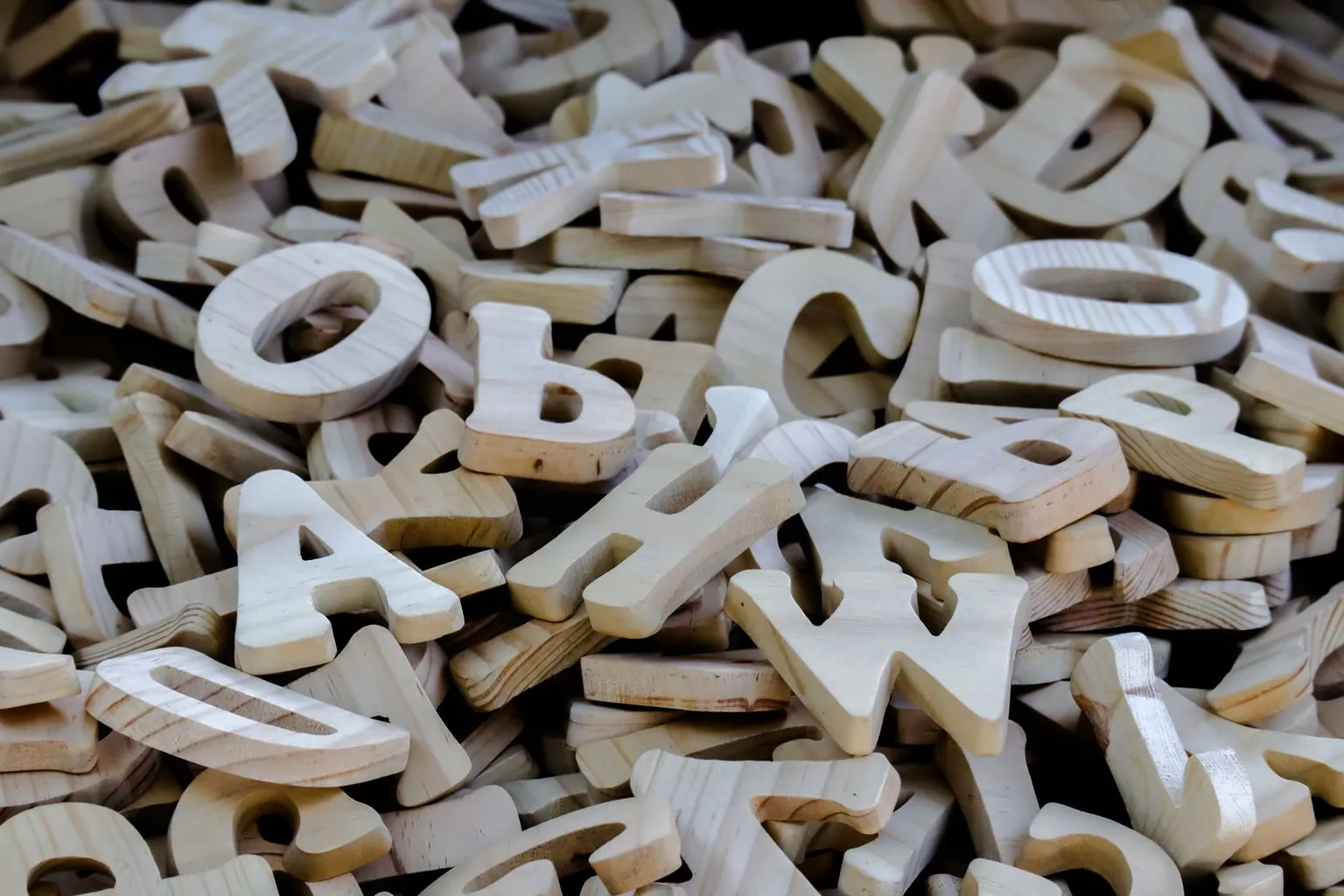 Un tas de lettres en bois clair mélangées.