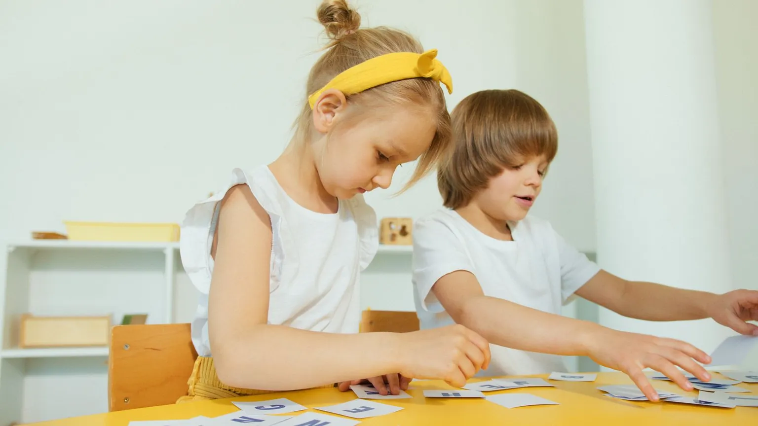 Deux enfants trient de petites cartes sur une table.