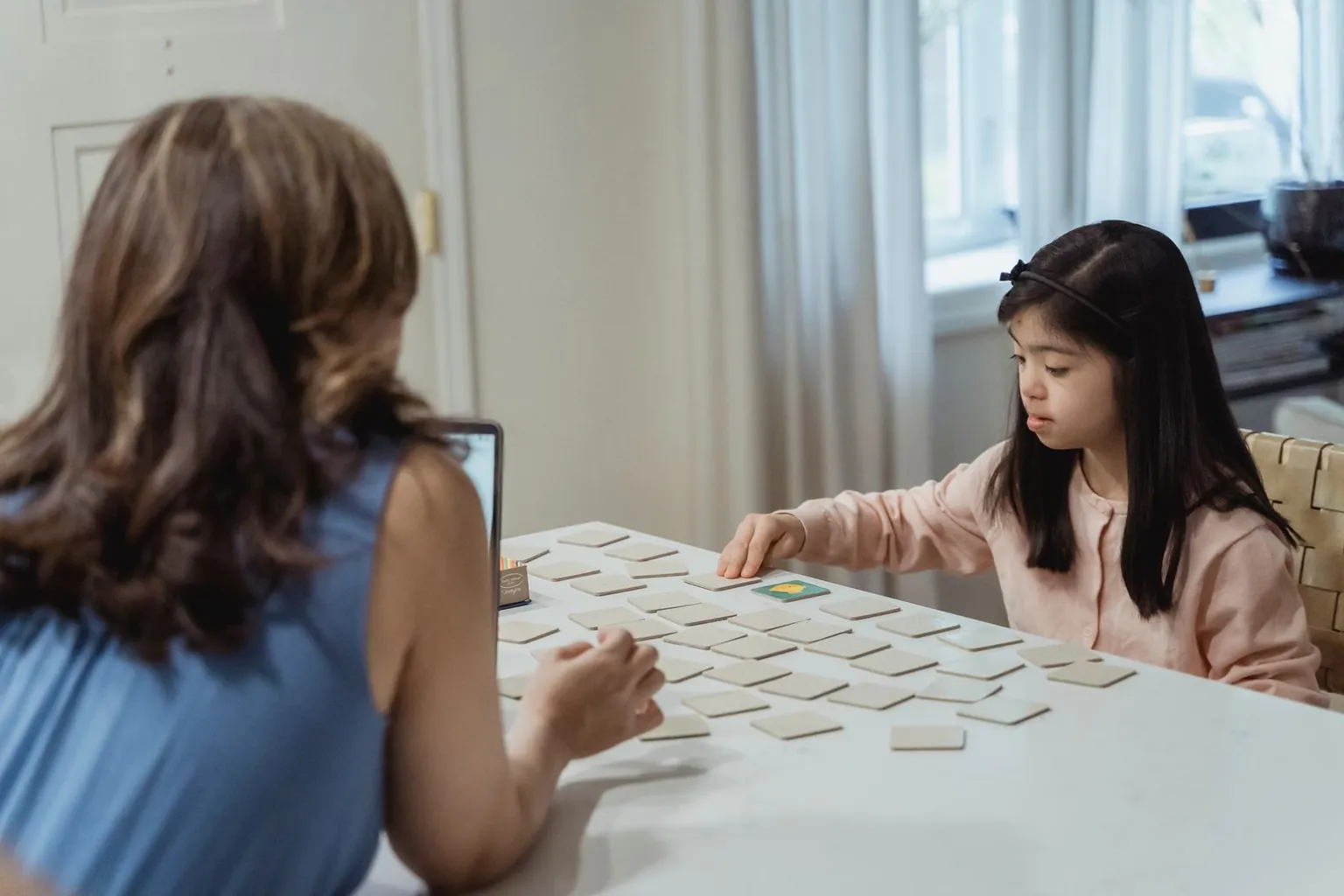 Une mère et sa fille jouent à un jeu de paires sur une table.
