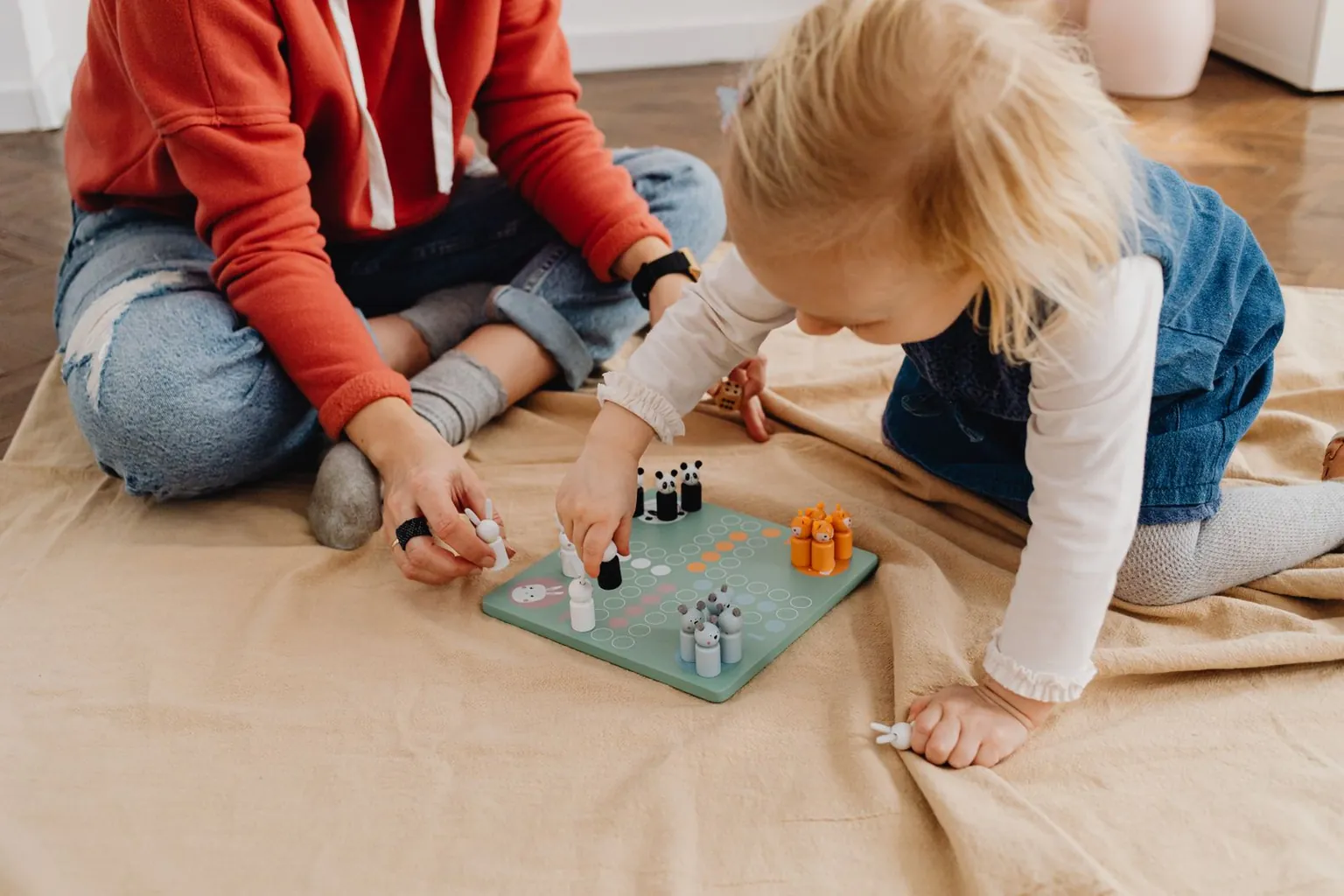 Deux enfants jouent à un jeu de plateau assis par terre.