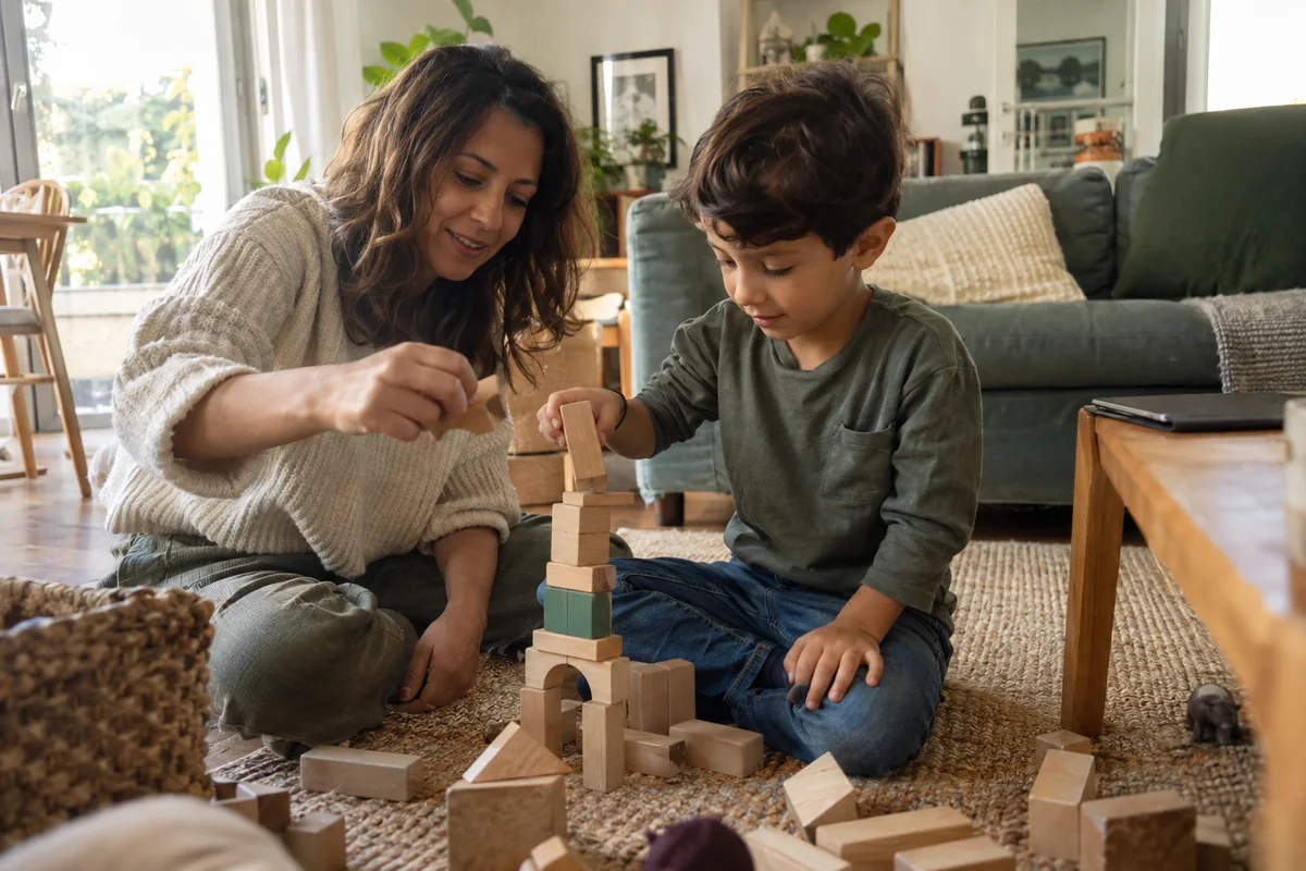 Un parent et son enfant construisent une tour en blocs pendant qu’une tablette reste posée à proximité.